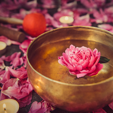 a charming bowl holding a pink flower surrounded by flickering candles, creating a peaceful ambiance